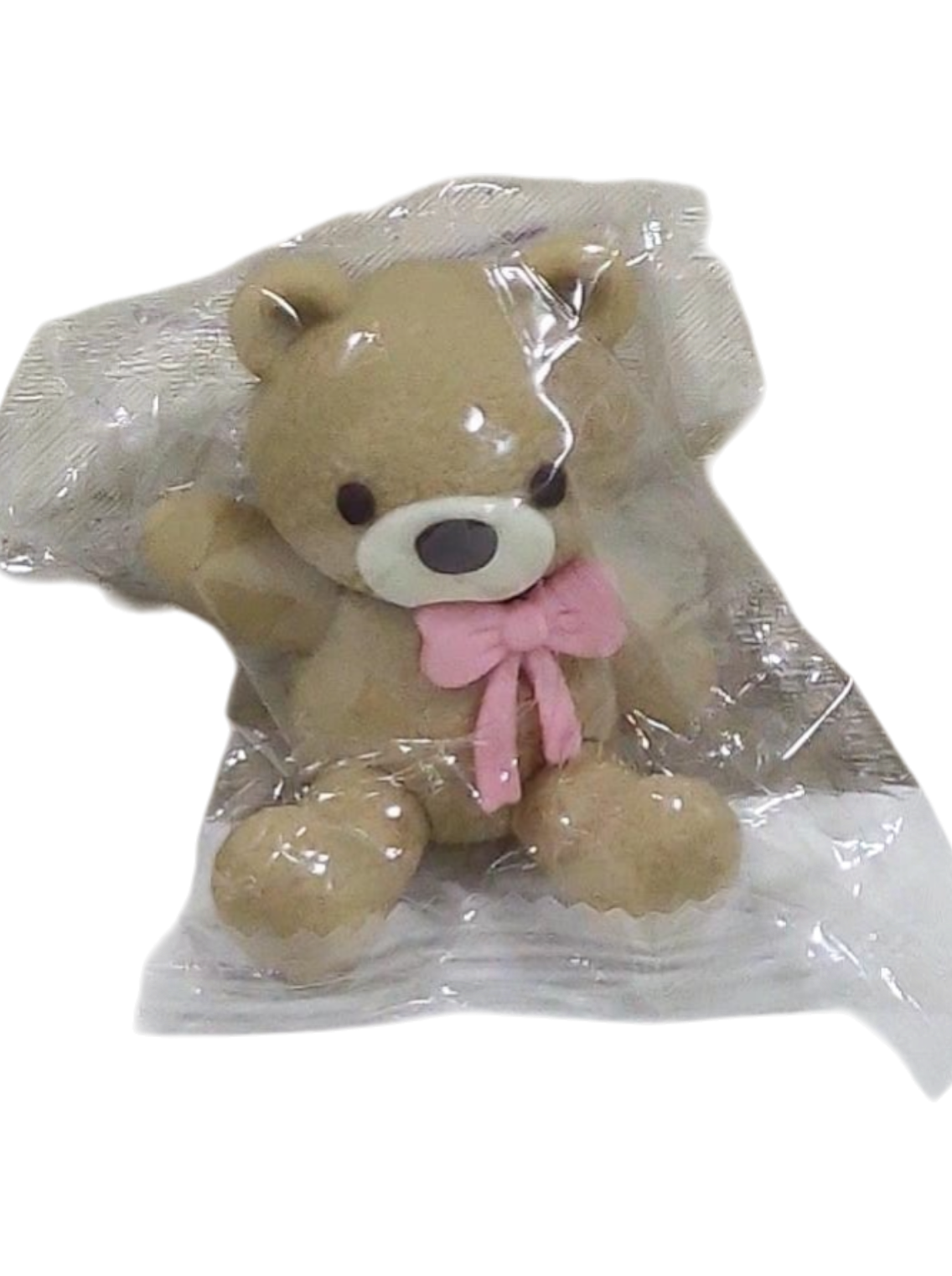 Plush teddy bear with a pink bow in transparent packaging on a transparent background