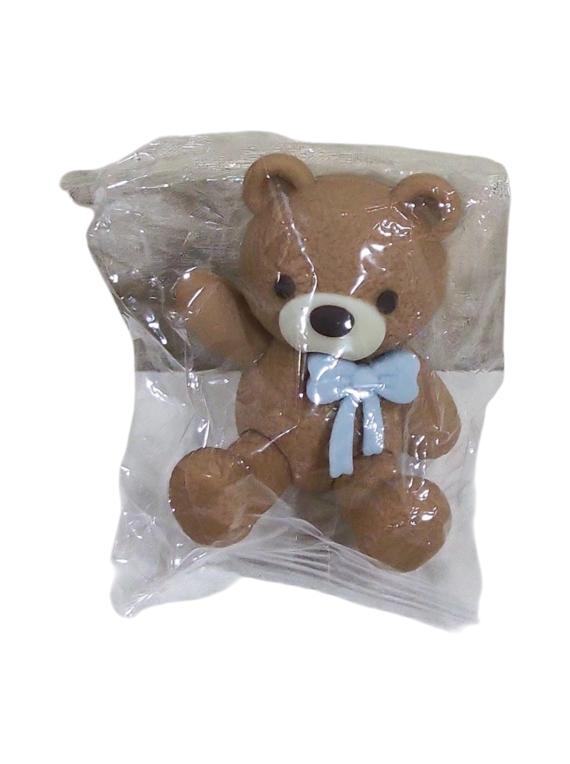 Plush teddy bear with a blue bow in clear packaging on a transparent background