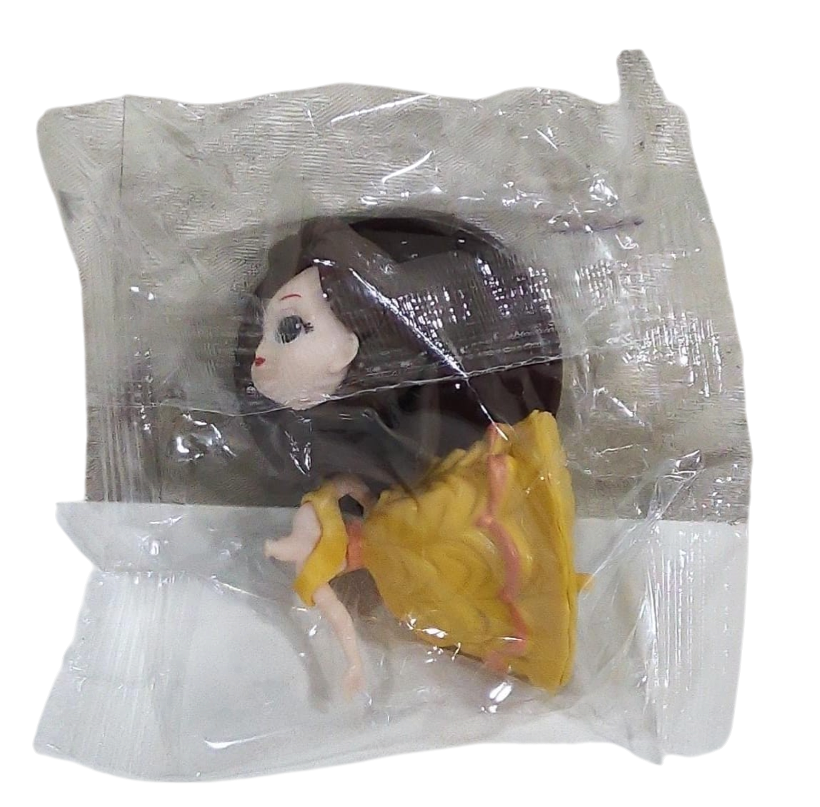 Toy figure of a girl in a yellow dress inside transparent plastic packaging on a transparent background