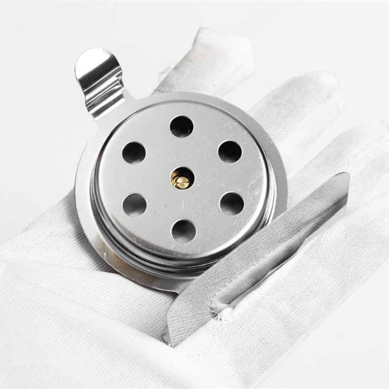 Metallic object with circular design and holes on a white fabric background