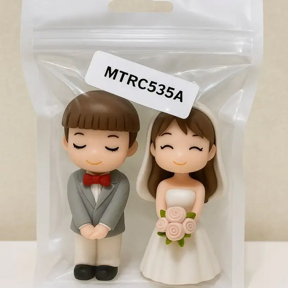 Miniature wedding couple toys in retail pouch labeled MTRC535A – boy in grey suit with red bowtie and girl in white gown holding pink roses, ideal for wedding cake toppers and crafts