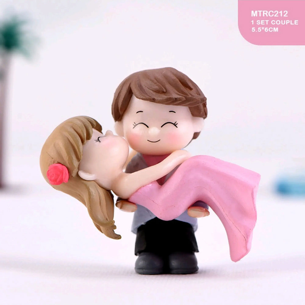 Miniature couple figurine of boy lifting girl in pink dress with red flower in hair – romantic wedding or anniversary cake topper, perfect for love-themed fondant cakes and couple decorations.