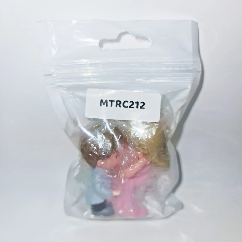 Packaged couple figurine set labeled MTRC212 – romantic cake topper featuring a boy carrying a girl, sealed in transparent plastic pouch for gifting or bakery decoration.