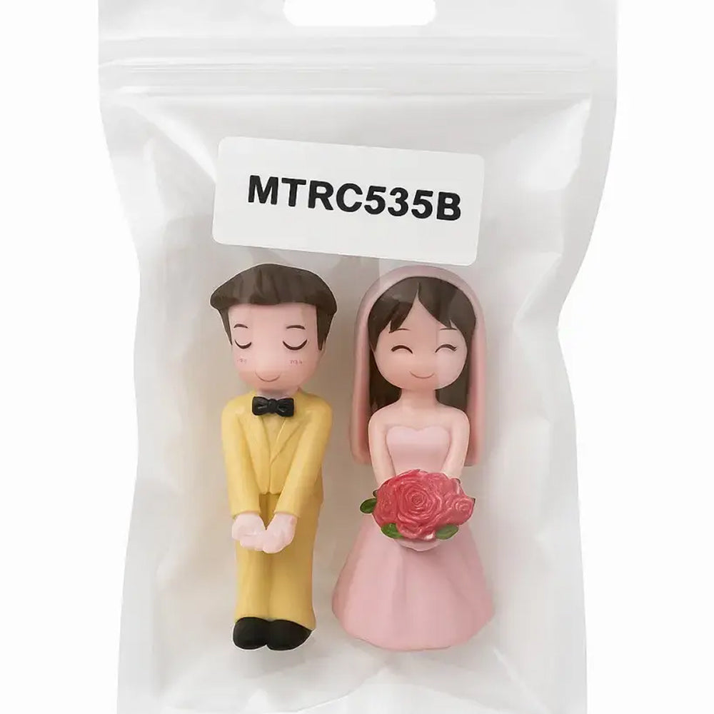 Packaged wedding figurine set labeled MTRC535B – bride in pink holding roses and groom in yellow suit, perfect for elegant wedding cake toppers and gift sets.
