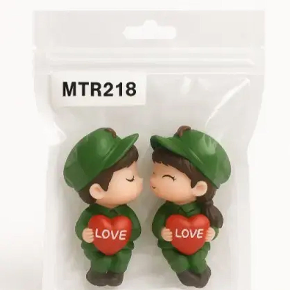 Cute love-themed couple figurines in soldier outfit holding red heart with ‘LOVE’ written on it – packed in a pouch labeled MTR218, great for couple gifts or Valentine's cake decorations