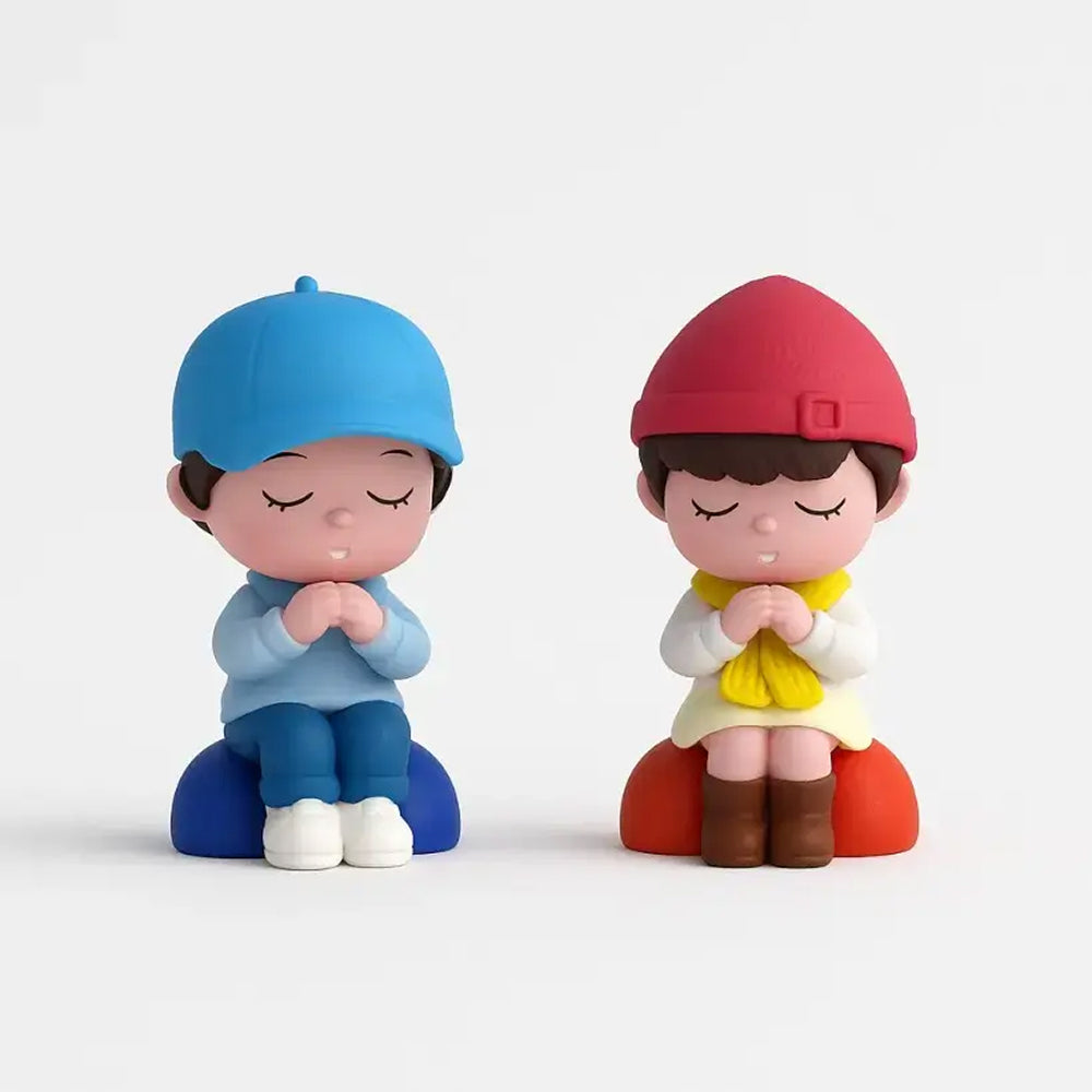 Unpackaged praying couple miniature set – boy in blue and girl in red and yellow, sitting on individual cushions with hands together – ideal for themed cakes or decorative displays.