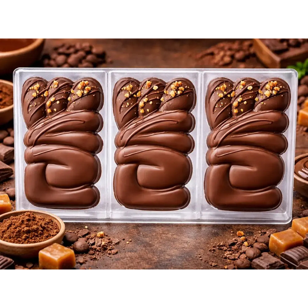 Polycarbonate mold Three chocolate in a clear plastic tray on a wooden surface with coffee beans and chocolate pieces.
