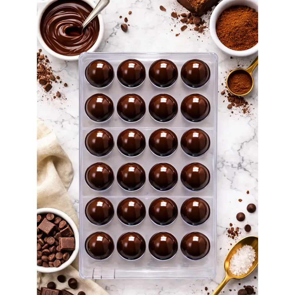 Polycarbonate  chocolate truffles with cocoa powder, chocolate pieces, and a spoon on a marble surface.