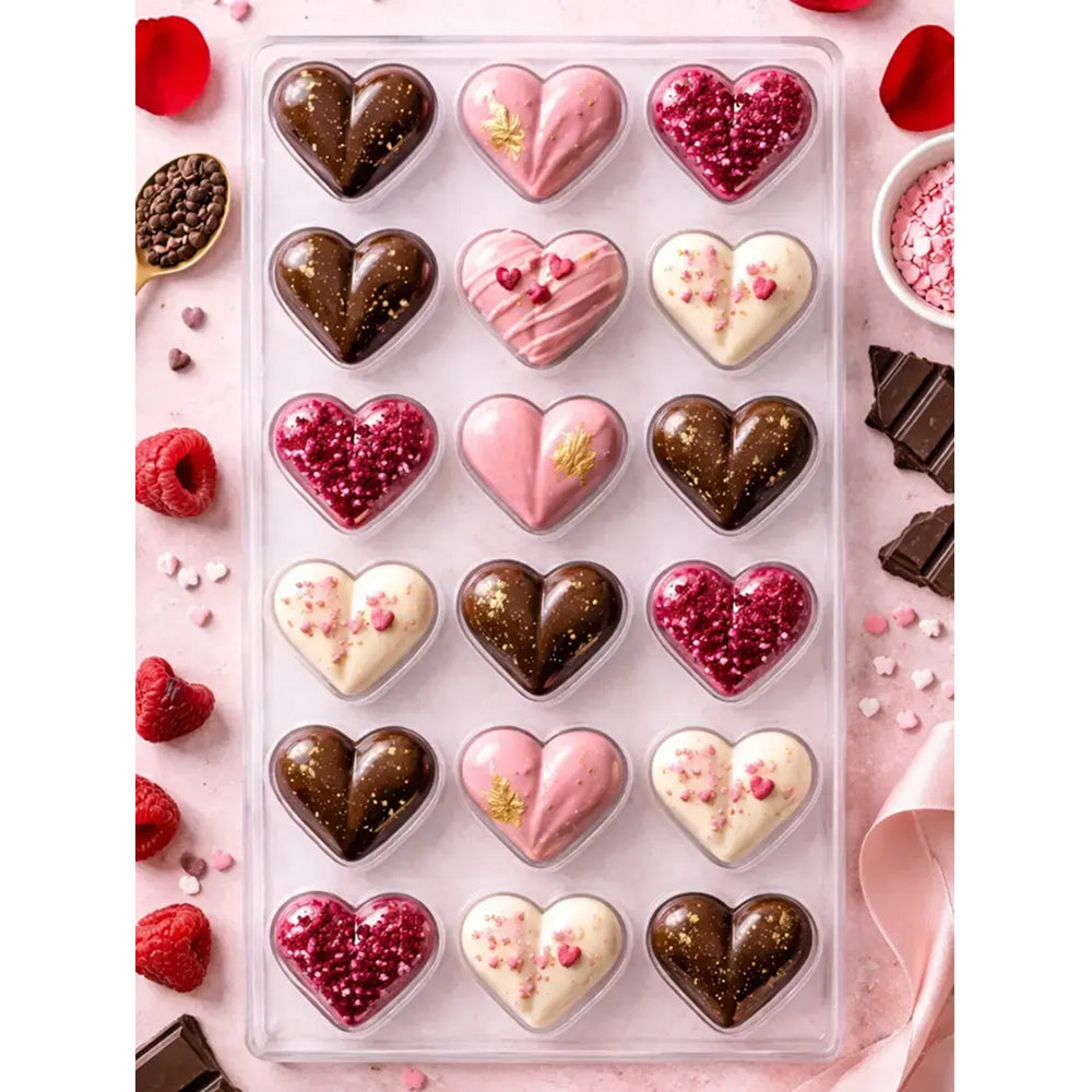 Assorted heart-shaped chocolates in a clear box on a pink background with red roses and chocolate pieces.