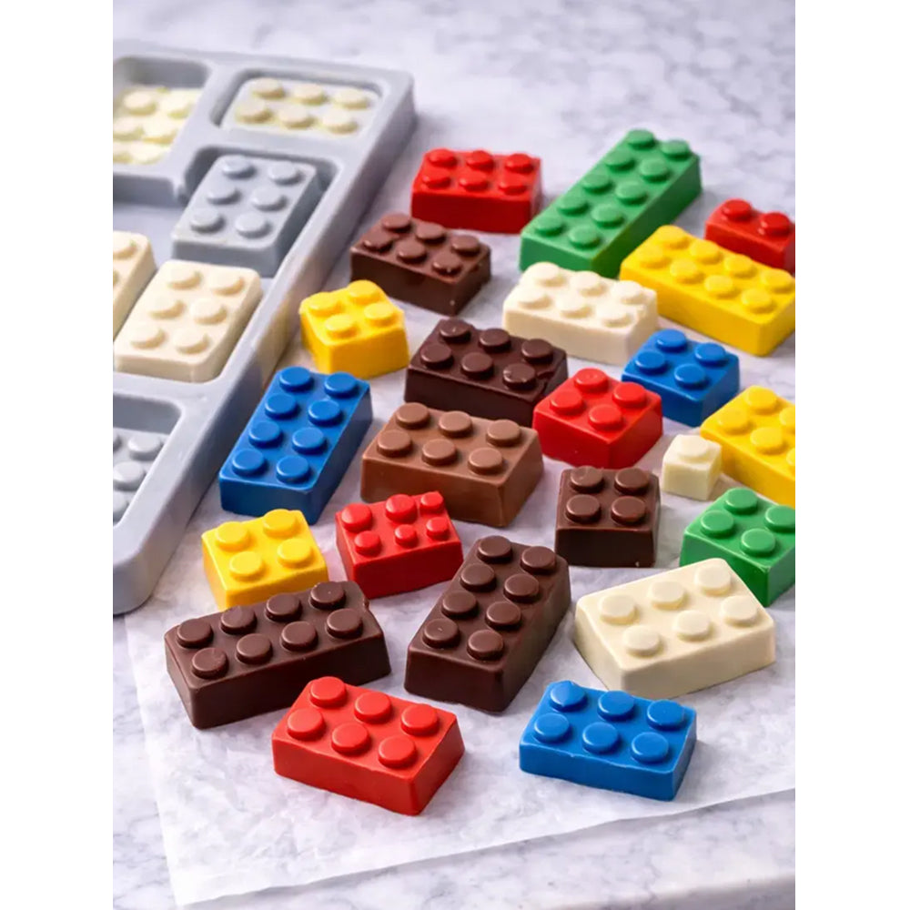 Colorful chocolate blocks shaped like building bricks on a marble surface