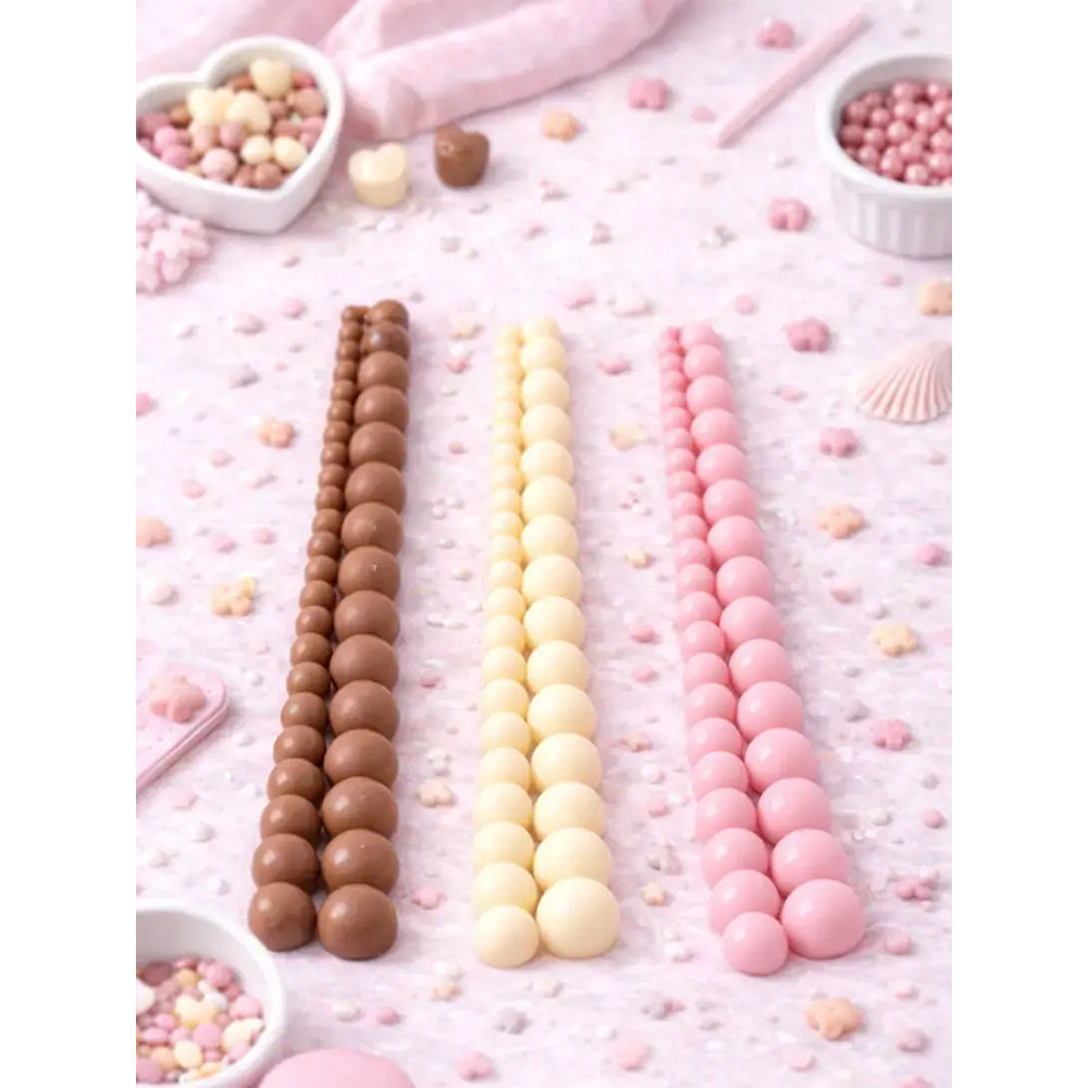 Three rows of chocolate, vanilla, and pink candy sticks on a pink background with small candies scattered around.