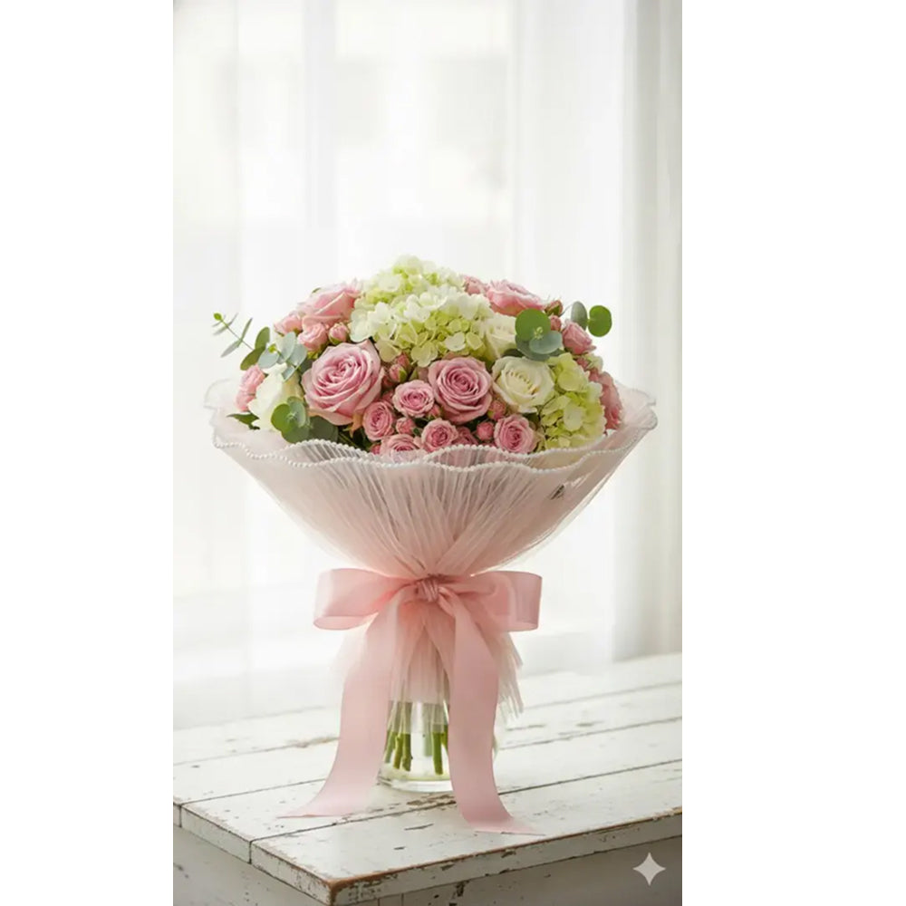 Bouquet of pink and white flowers with a pink ribbon on a white surface.