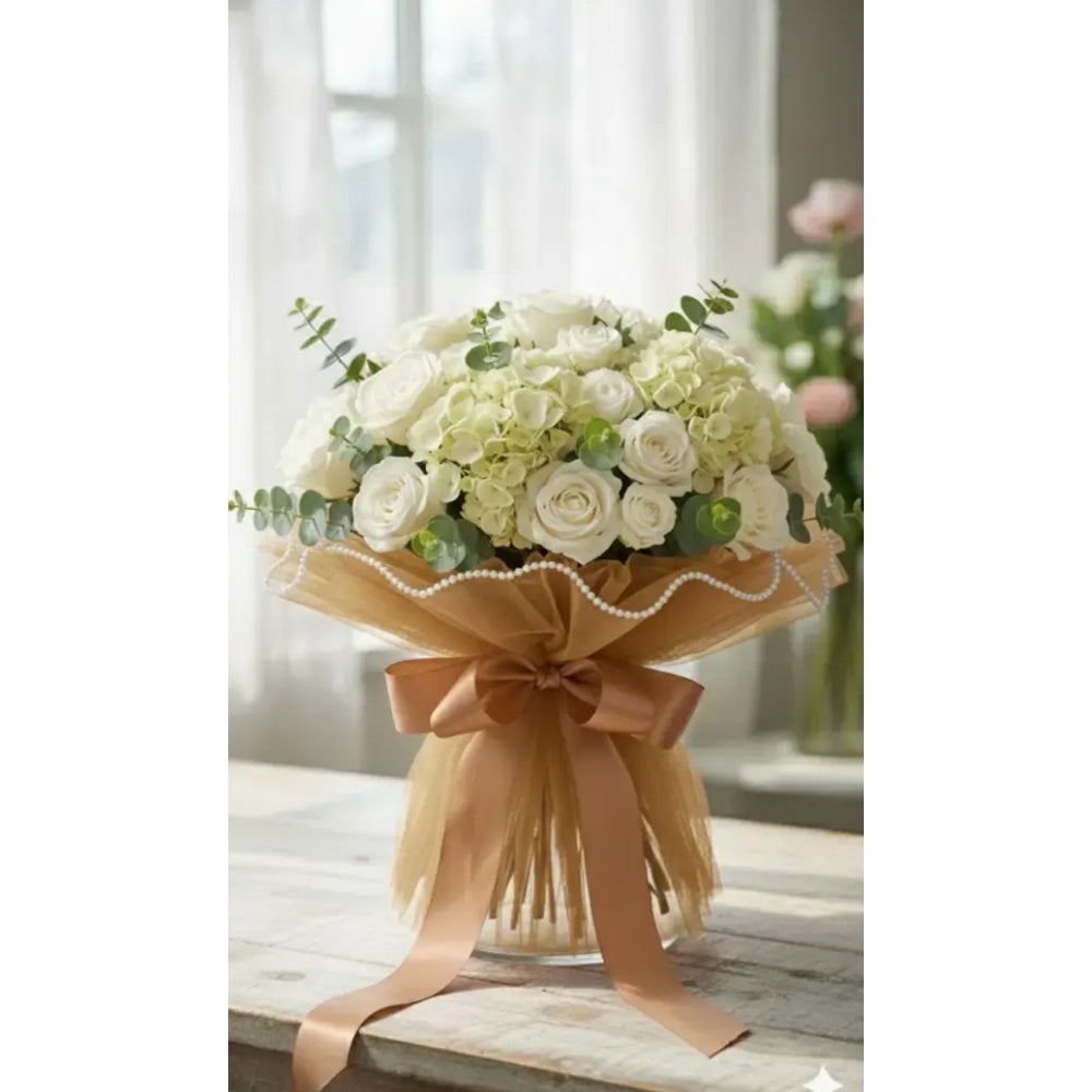 Bouquet of white and green flowers wrapped with a beige ribbon on a wooden surface.