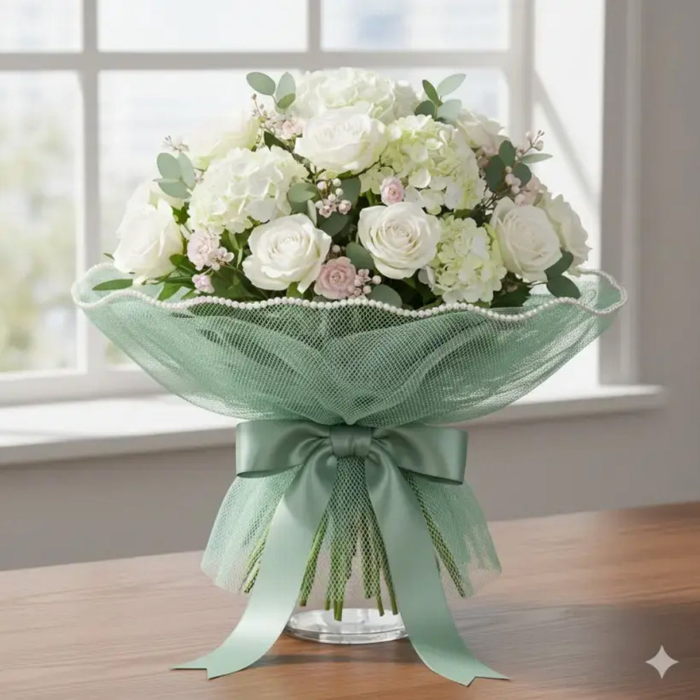 Bouquet of white and green flowers with a green ribbon on a wooden table.