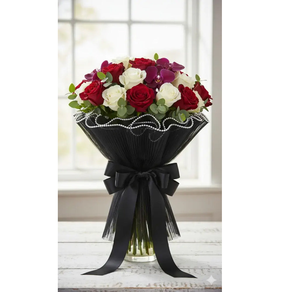 Bouquet of red, white, and purple flowers wrapped in black paper with a bow on a white surface.
