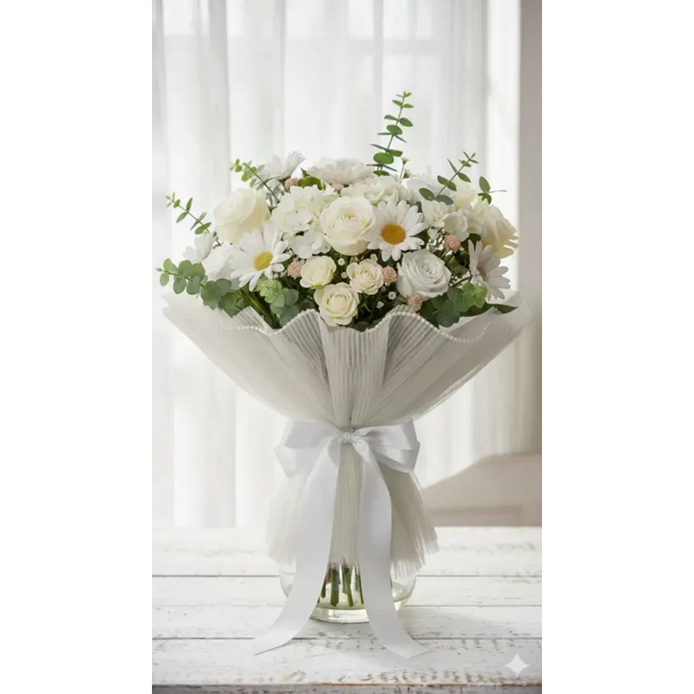 Bouquet of white and green flowers in a decorative vase with a white ribbon on a light wooden surface.