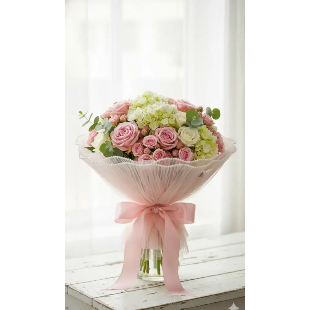 Bouquet of pink and green flowers with a pink ribbon on a white surface.
