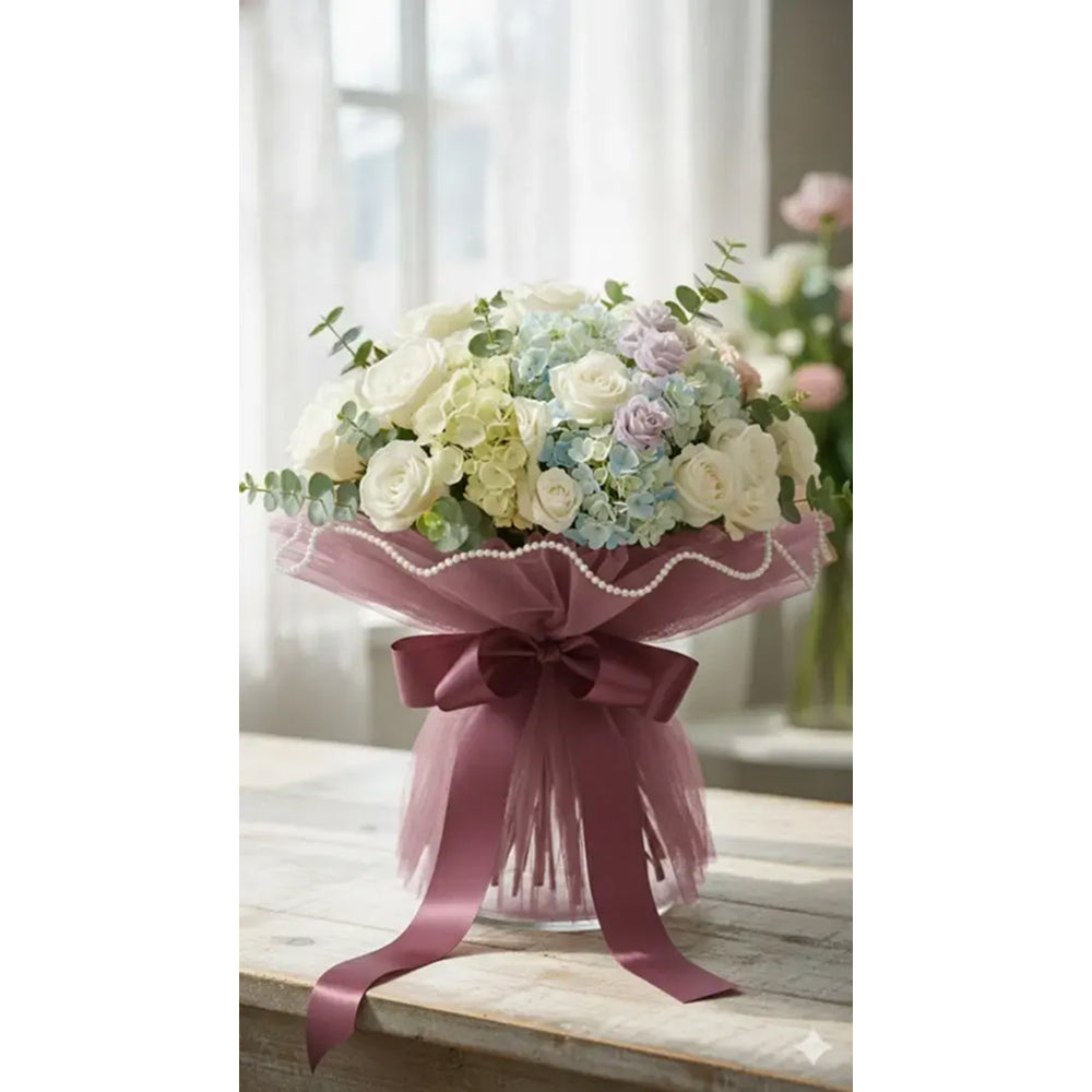 Bouquet of flowers wrapped in pink paper with a bow on a wooden surface.