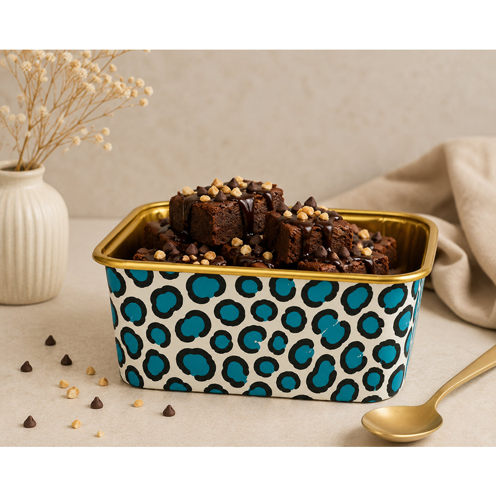 Square container with blue and black polka dot pattern filled with brownies on a beige surface.