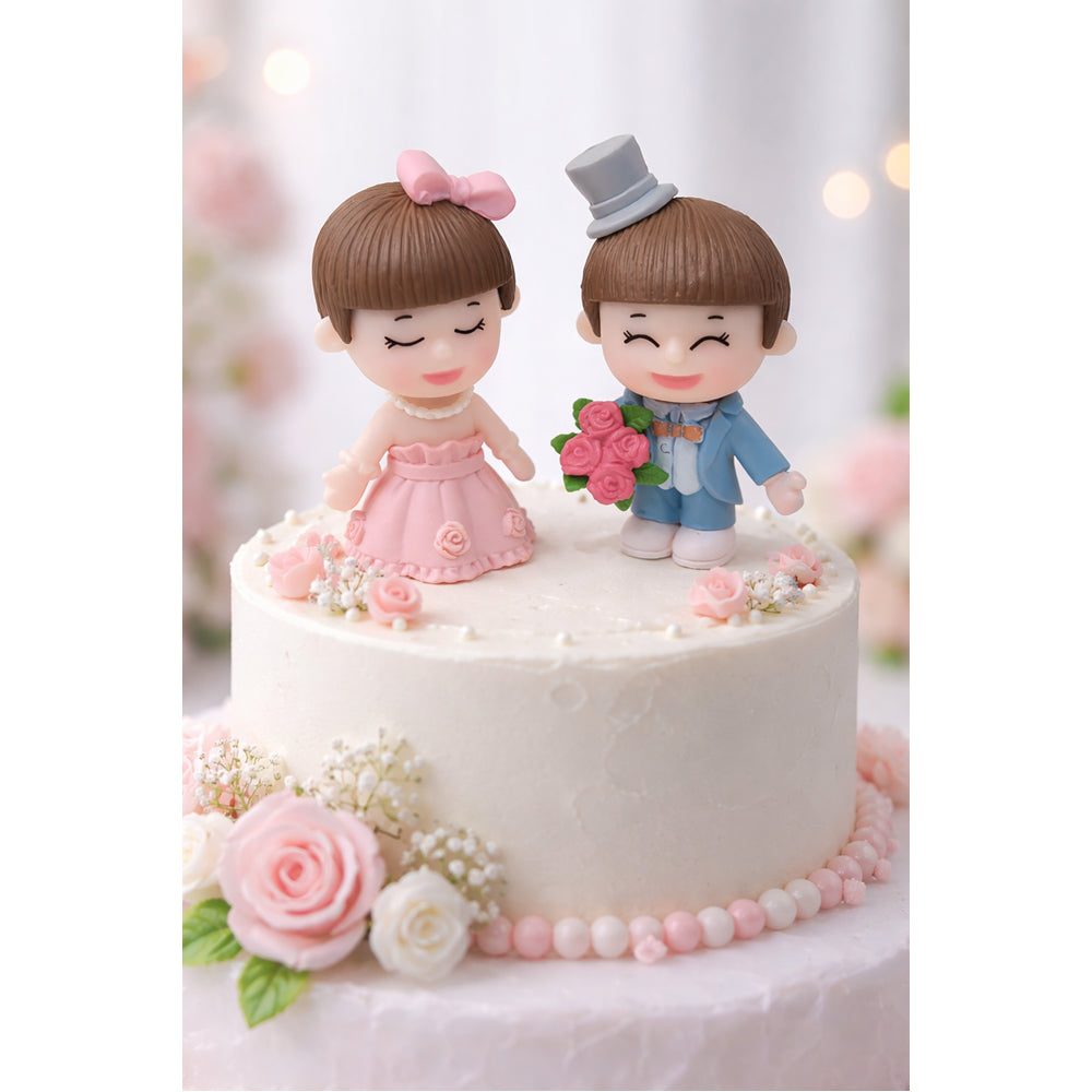 Two Miniatures Wedding cake topper with figurines of a bride and groom on a white cake.