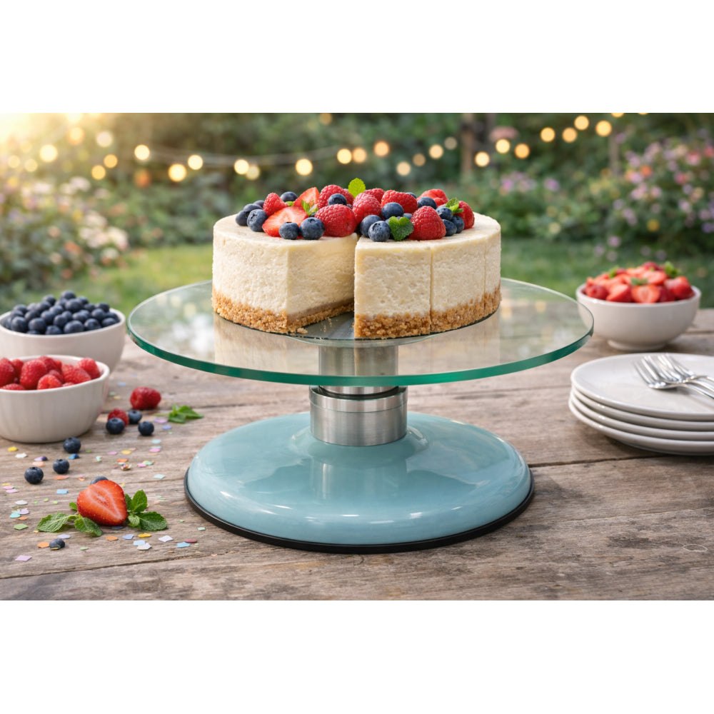 Two layered cheesecake on a glass cake stand with berries on top, set outdoors.