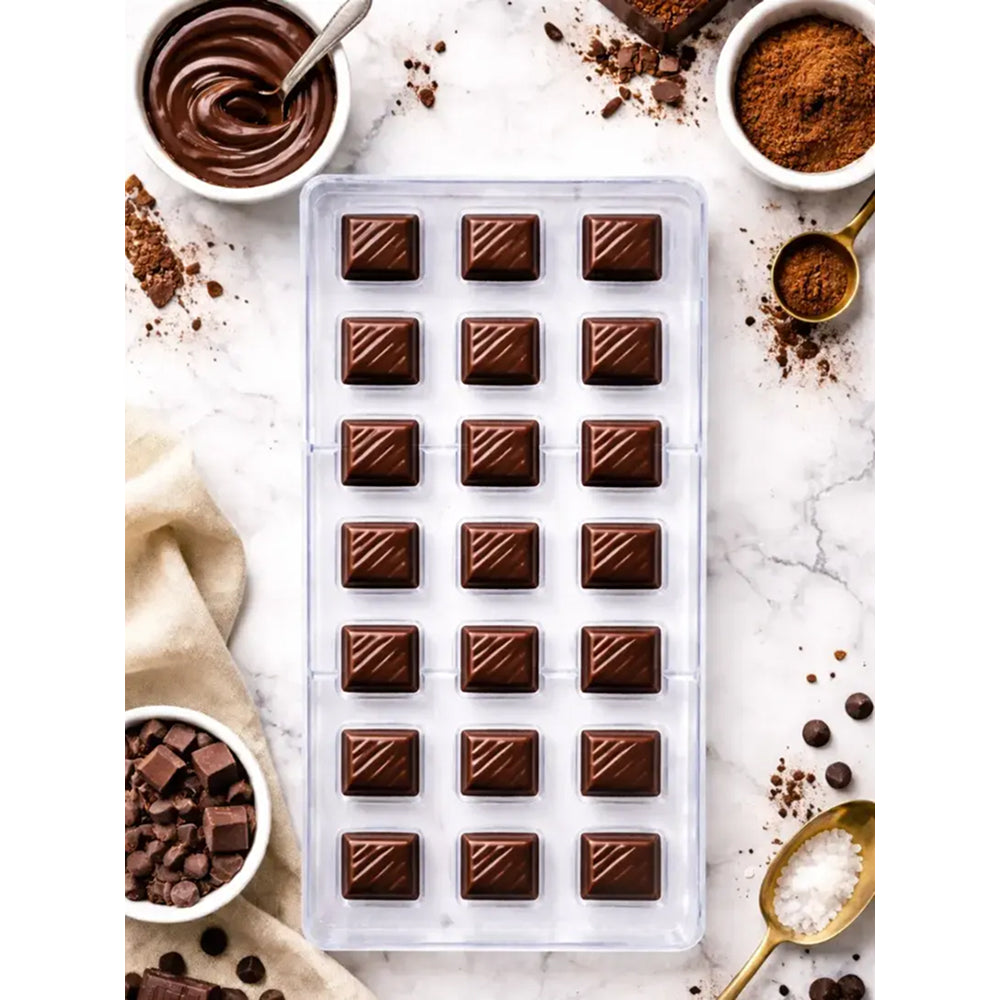 Polycarbonate Chocolate mold with chocolate bars on a marble surface with chocolate ingredients.