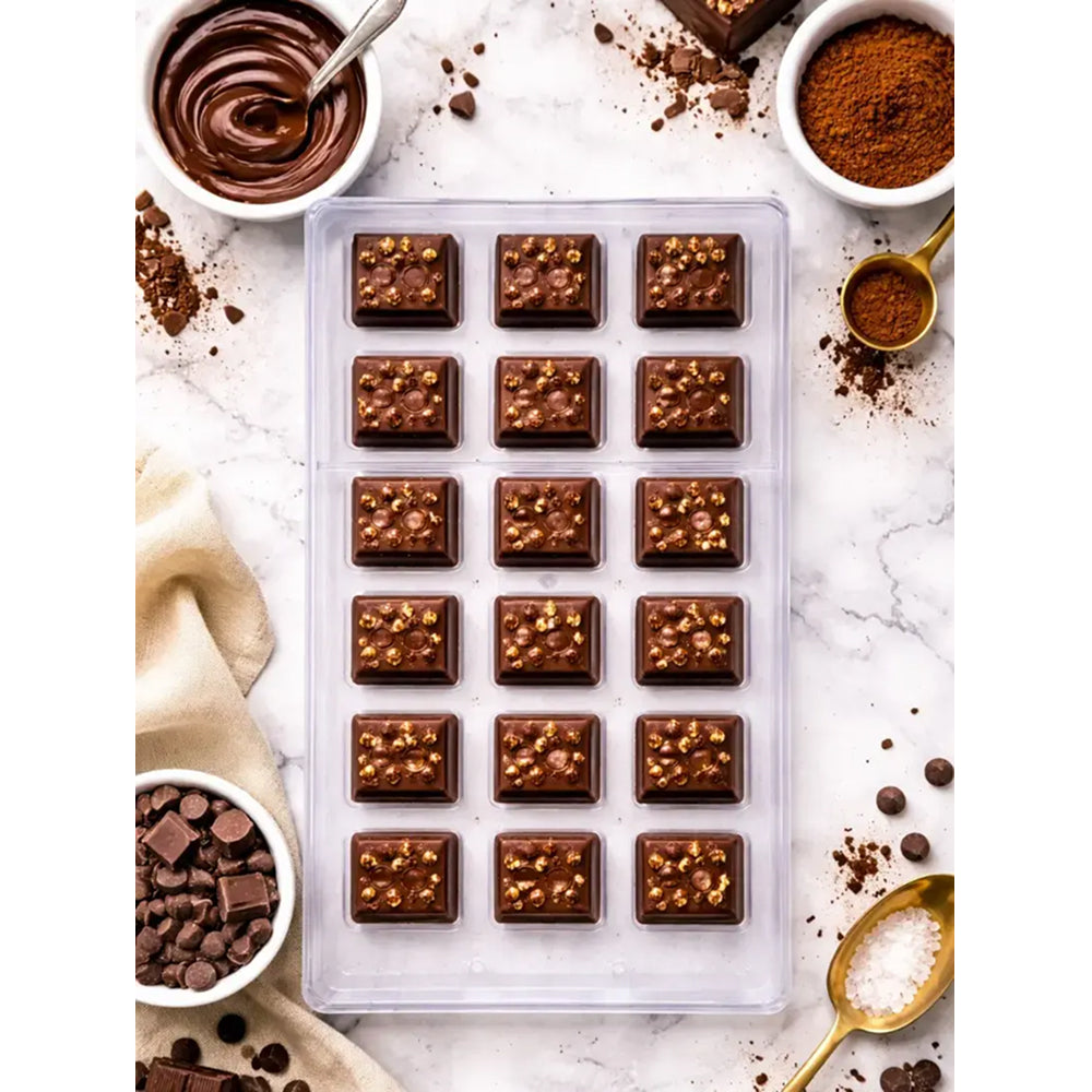 Polycarbonate Chocolate mold with filled chocolate bars on a marble surface with chocolate ingredients.