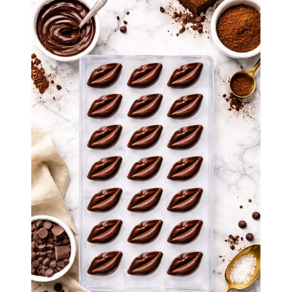 polycarbonate Chocolate mold with lip-shaped cavities on a marble surface with cocoa powder and chocolate chips.