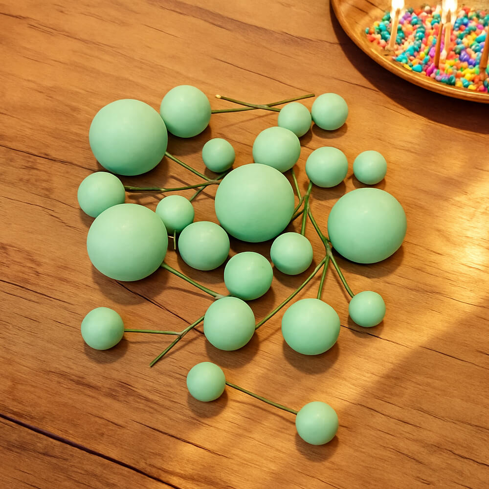 Green Matte Decorative faux balls displayed on a table with a bowl of colorful sprinkles in the corner, perfect for creative cake decorating.
