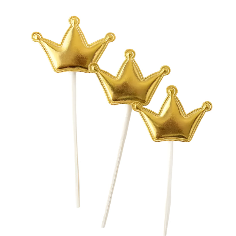 Three gold crown-shaped cake toppers on sticks against a white background