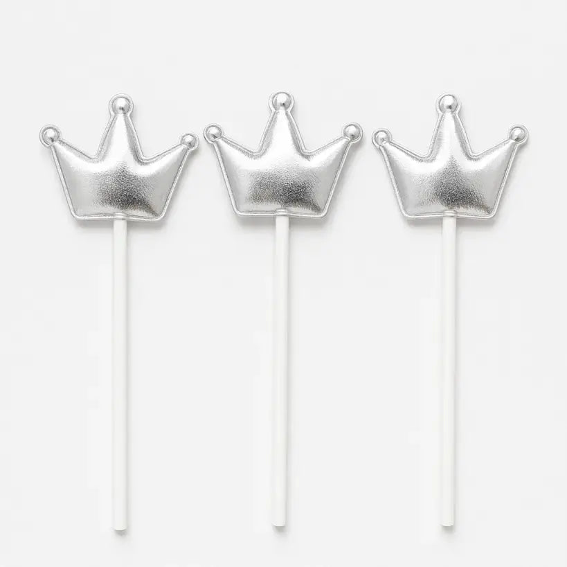 Three silver crown-shaped cake toppers on sticks against a white background