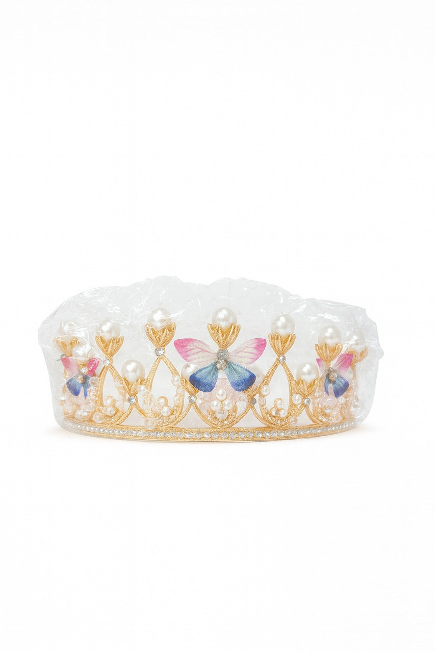 Decorative crown topper with floral and butterfly design in its packet on a white background