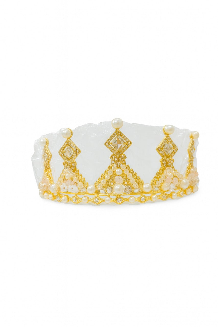 White crown topper with gold detailing in its packet on a white background