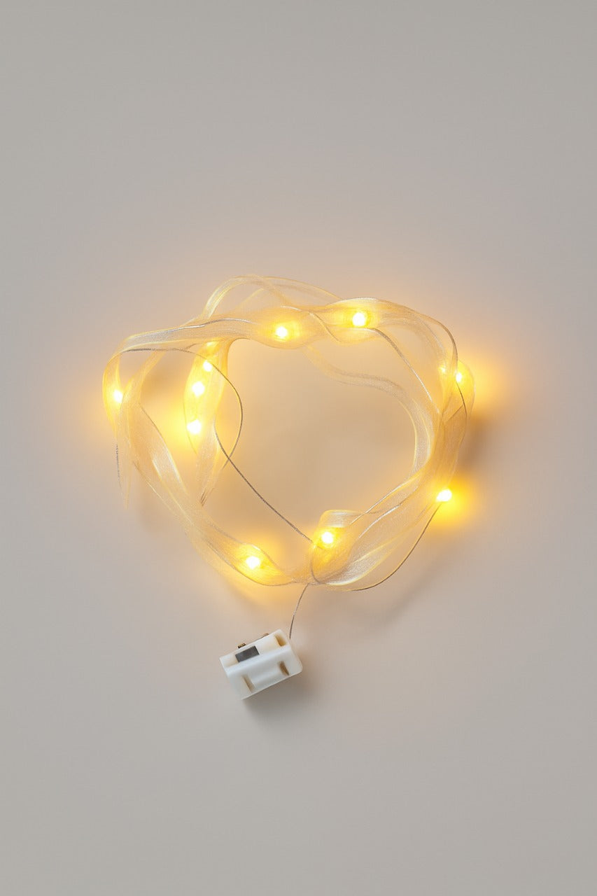Warm White LED ribbon string lights topper with a white plug on a light gray background