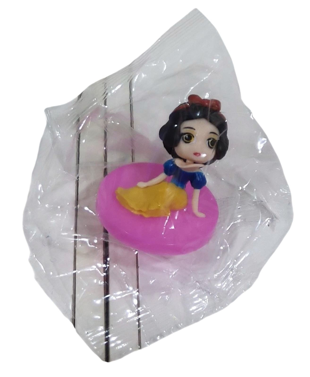 Toy figure of a princess in a blue dress and yellow skirt on a pink platform in a clear transparent bag on a transparent background