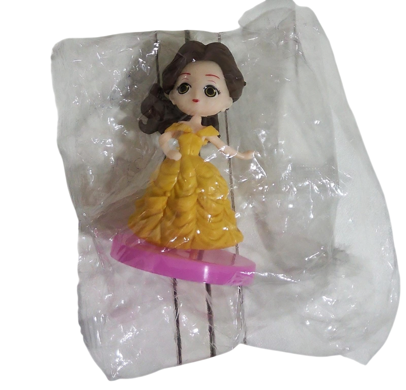 Toy figure of a character in a yellow dress with a pink bottom, in a clear transparent bag on a transparent background