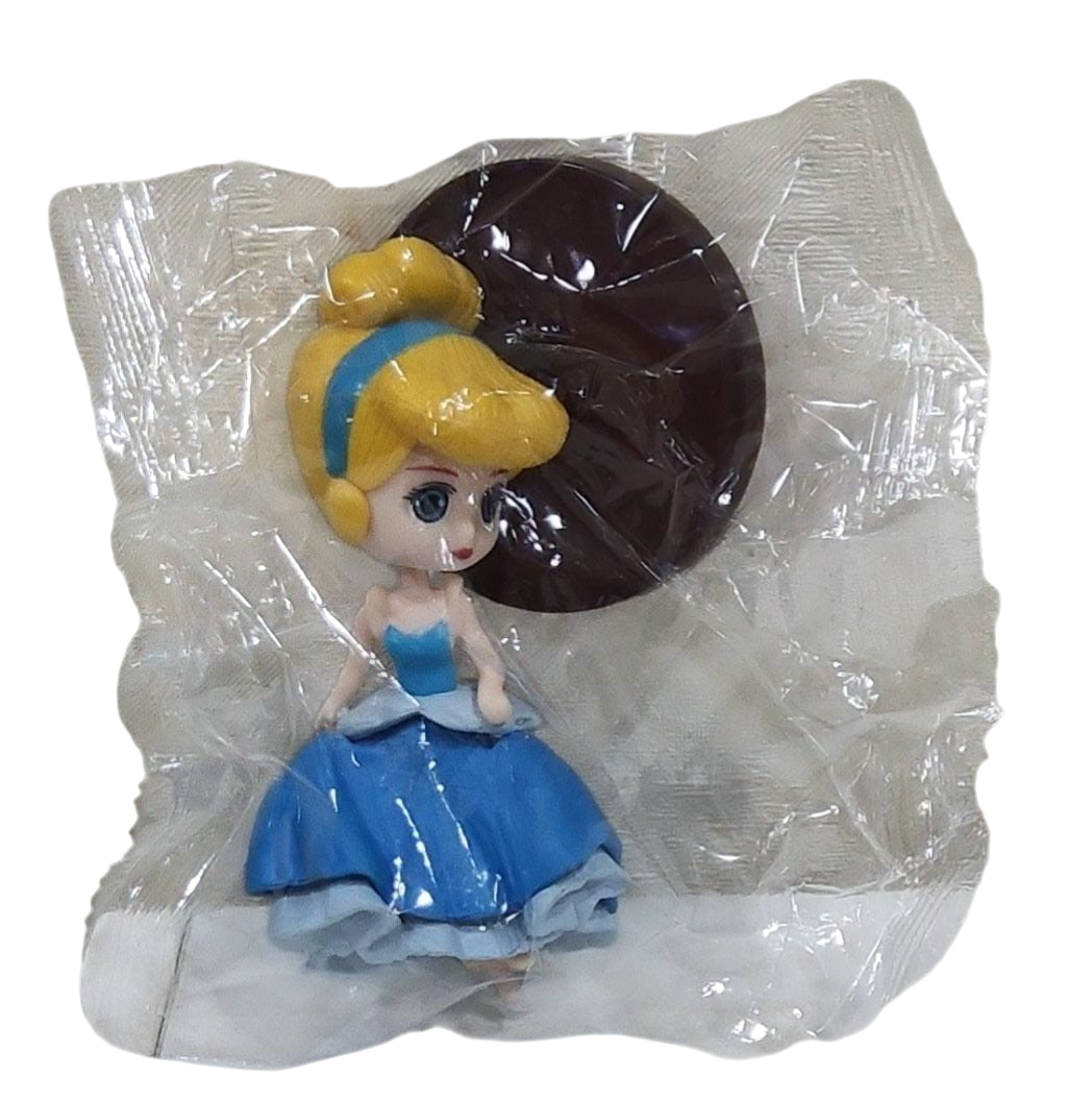 Toy figure of a princess in a blue dress with yellow hair, wrapped in transparent plastic on a transparent background.