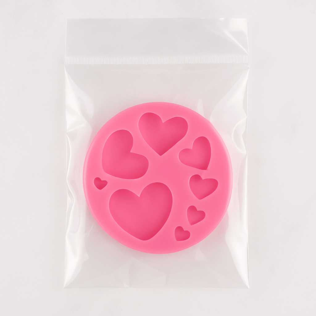 Pink silicone mold with heart shapes in transparent packaging on a white background