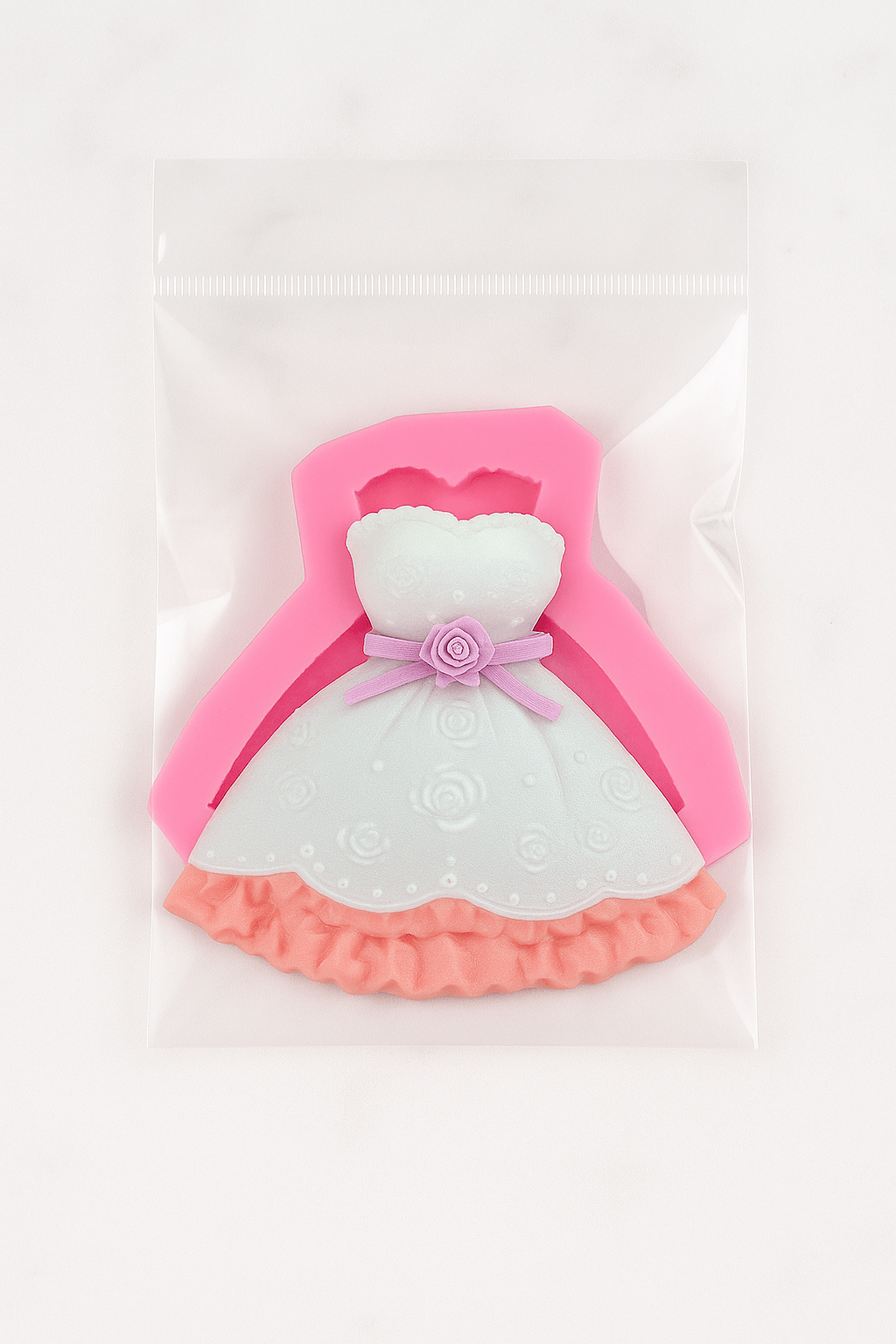 Pink and white dress-shaped fondant mold on a light pink background