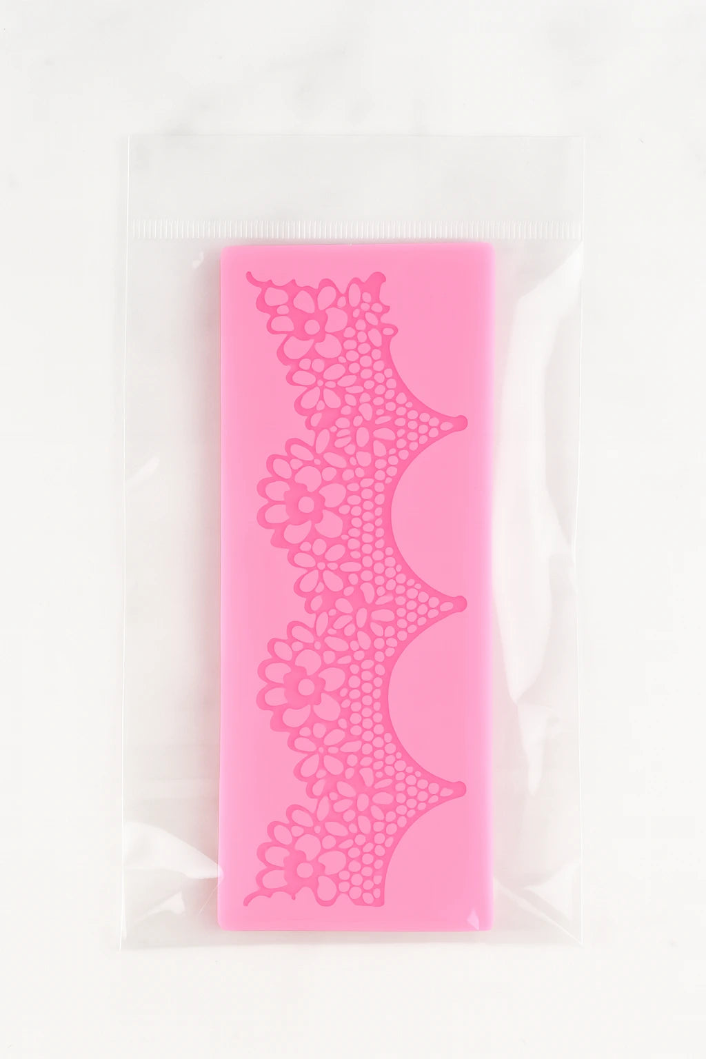 Pink fondant lace mat in its packet on a white background