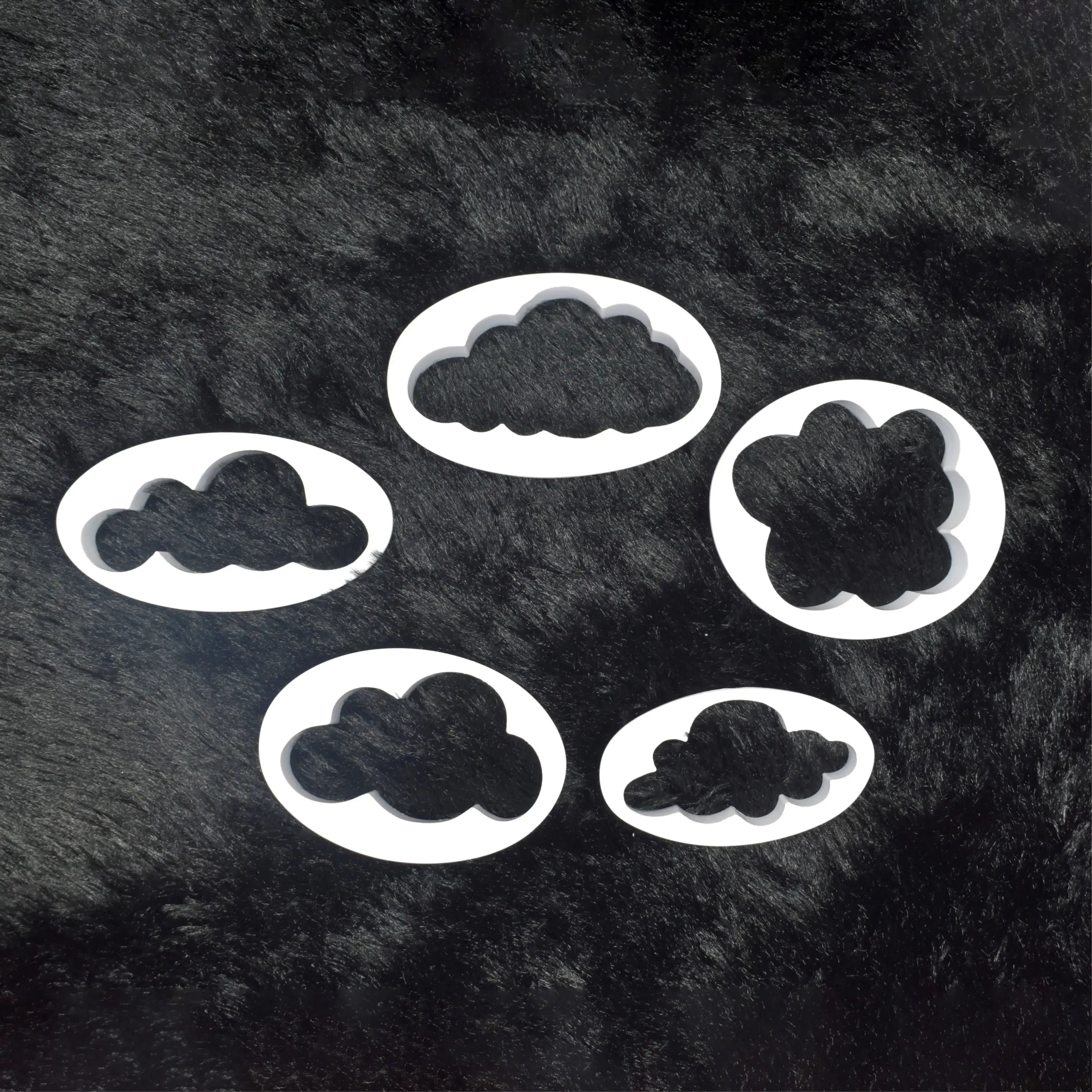 Set of cloud-shaped cookie cutters on a black textured background