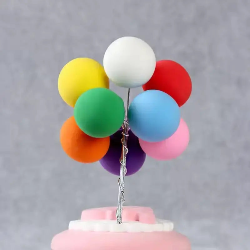 Colorful balloon cake topper on a cake with a gray background